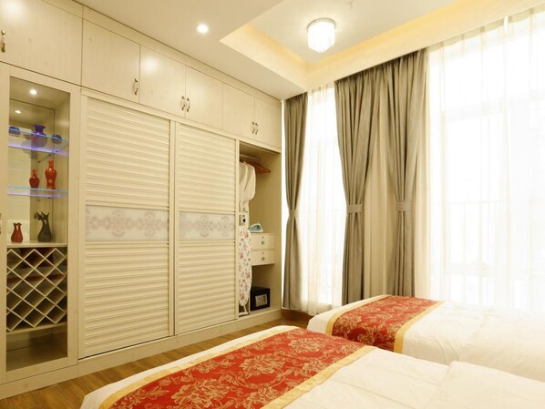Habitación de hotel con dos camas, un armario con espejo, una mesita y una ventana con cortinas.