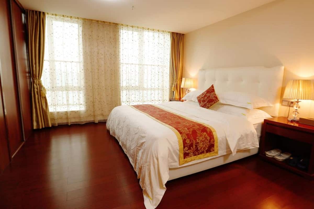 A hotel room with a large bed, a nightstand, and a window with curtains.