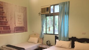 Una habitación con dos camas, una mesita, una tetera y un ventanal con cortinas.