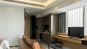 A modern hotel room with a leather sofa, a dining table, and a TV. - Pengman International Apartment Hotel (Guangzhou)