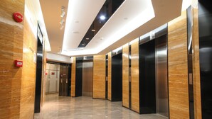 A modern elevator area with polished marble floors and wood paneling on the walls. - Pengman International Apartment Hotel (Guangzhou)