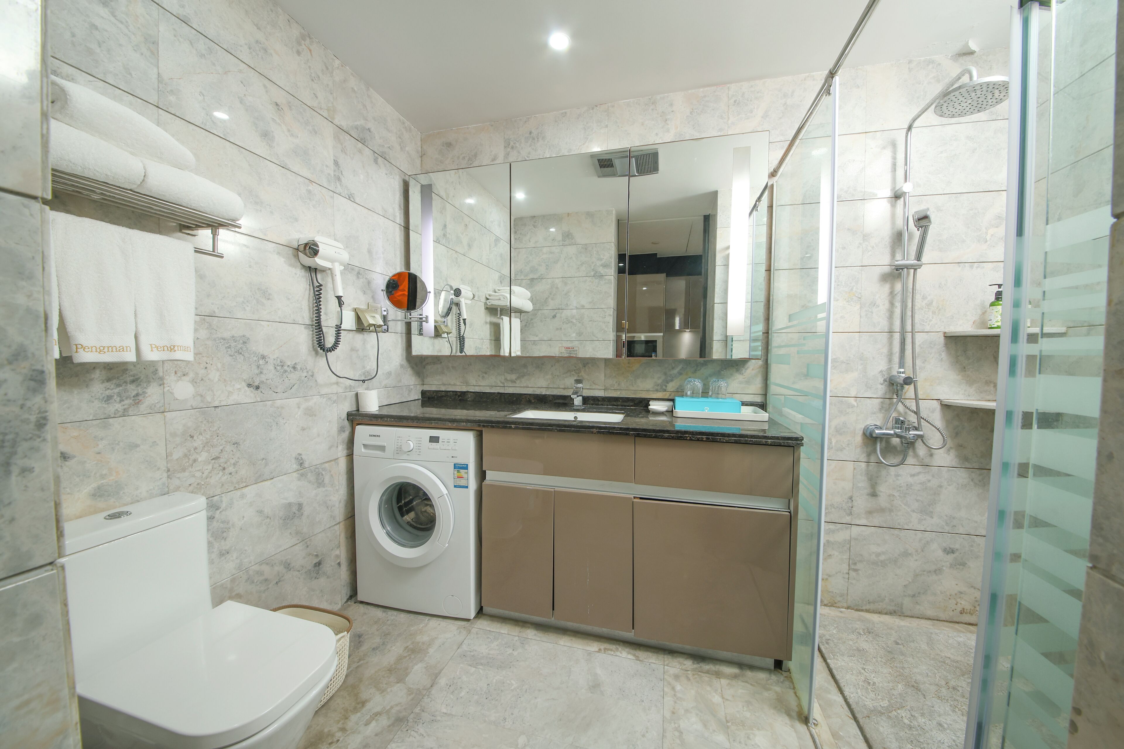Ein modernes Badezimmer mit Waschmaschine, Toilette, Waschbecken und Dusche.