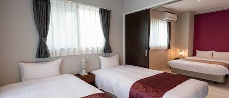 Une chambre d’hôtel avec deux lits, une table de chevet avec une lampe, une fenêtre avec des rideaux et un appareil de climatisation.