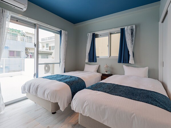 Une chambre d’hôtel avec deux lits, une fenêtre avec des rideaux et une vue sur les bâtiments environnants.