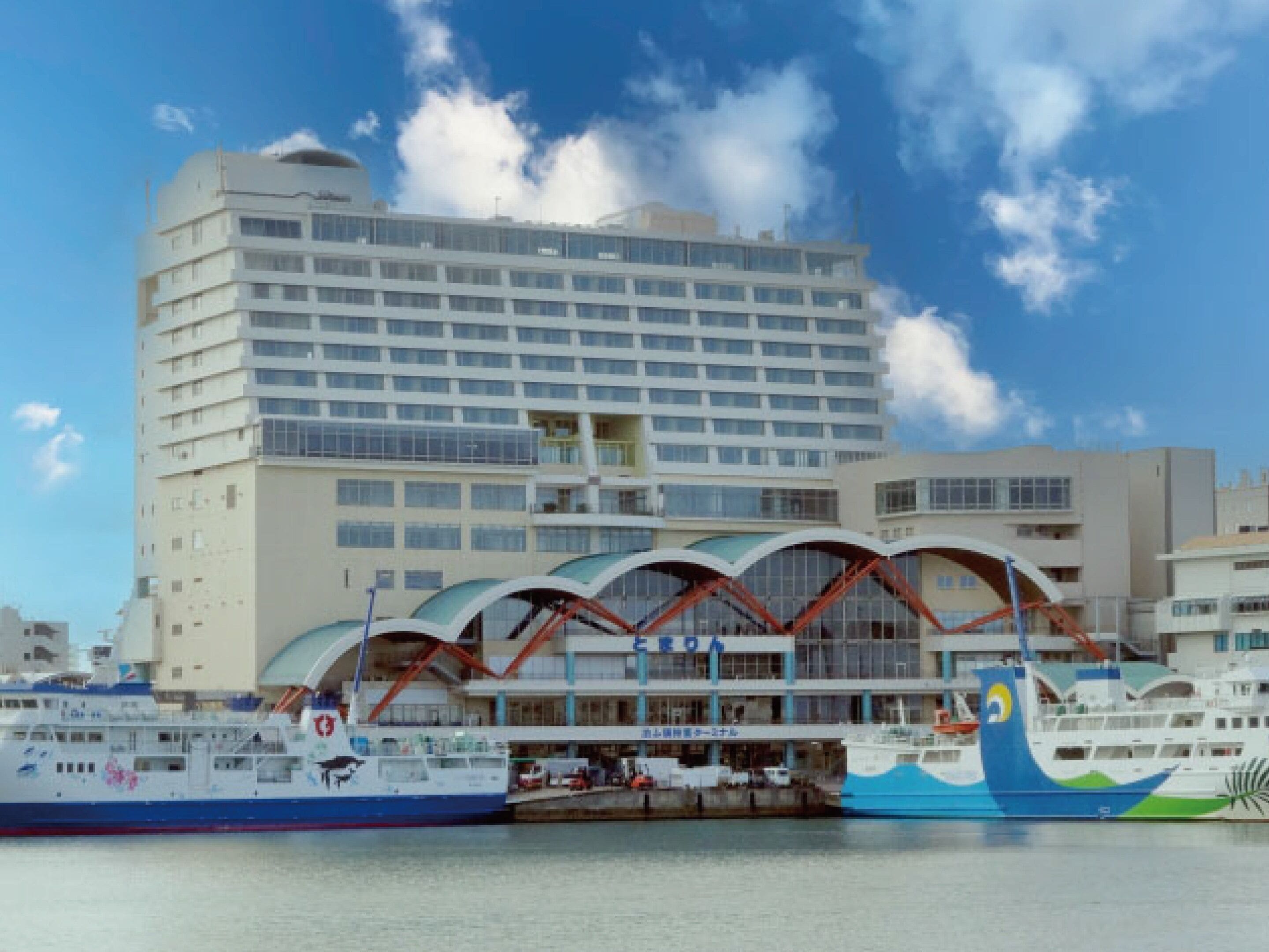 A modern hotel with a large glass facade and a distinctive curved roof structure.