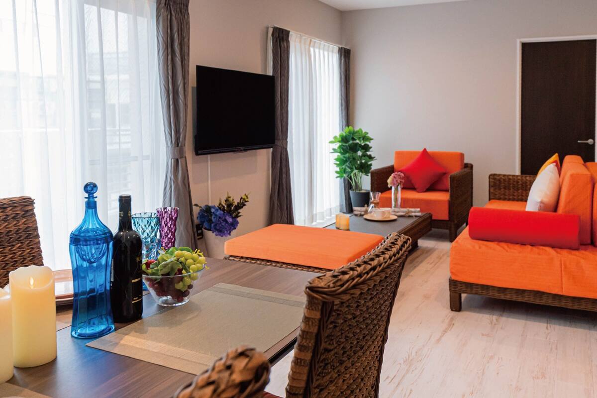 A modern living room with a sofa, a dining table with candles, and a TV mounted on the wall.