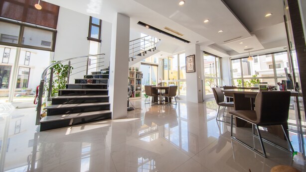 A modern hotel lobby with a staircase, a dining area, and large windows. - HI One One (Magong)
