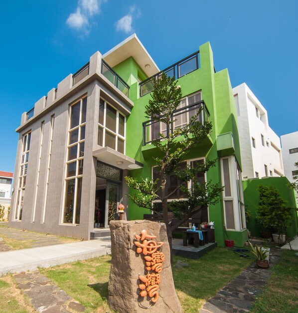 Un edificio moderno con amplios ventanales y fachada verde.