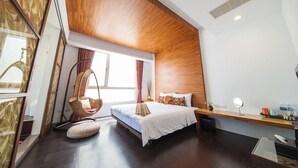A modern hotel room with a wooden ceiling, a large bed with white linens, a hanging chair, a bedside table with a lamp, and a view of the outdoors. - HI One One (Magong)