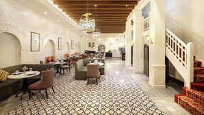 A spacious hotel lobby with a high ceiling, patterned floor tiles, and a staircase with red carpeted steps. - Kokoon Hotel Surabaya (Surabaya)