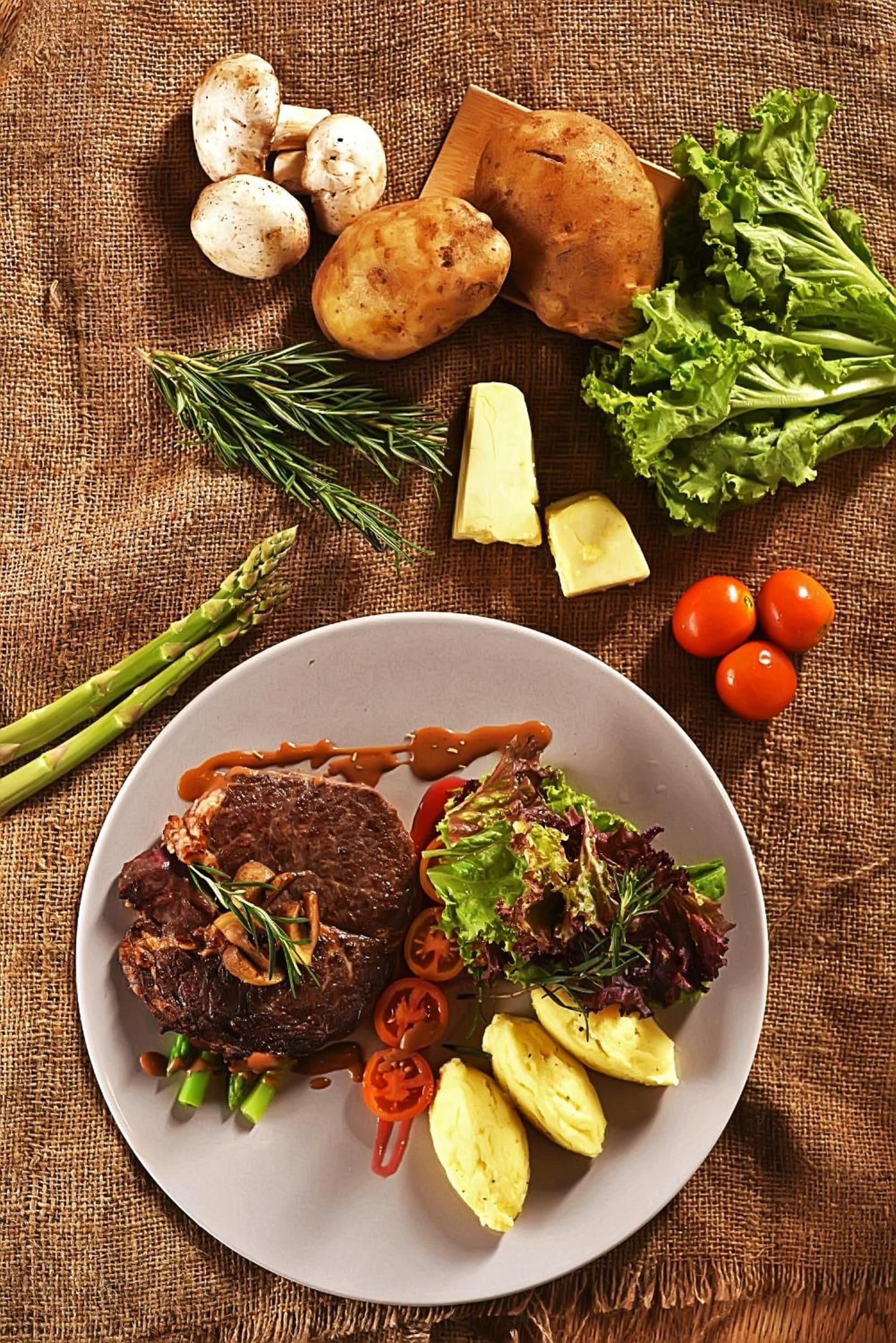 A plate with steak, mushrooms, asparagus, and a salad.