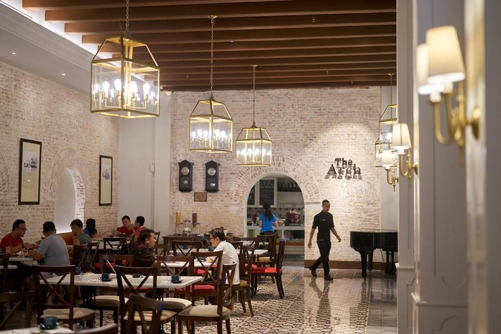 Un restaurant aux murs en briques, au plafond orné de poutres en bois et aux luminaires hexagonaux suspendus.