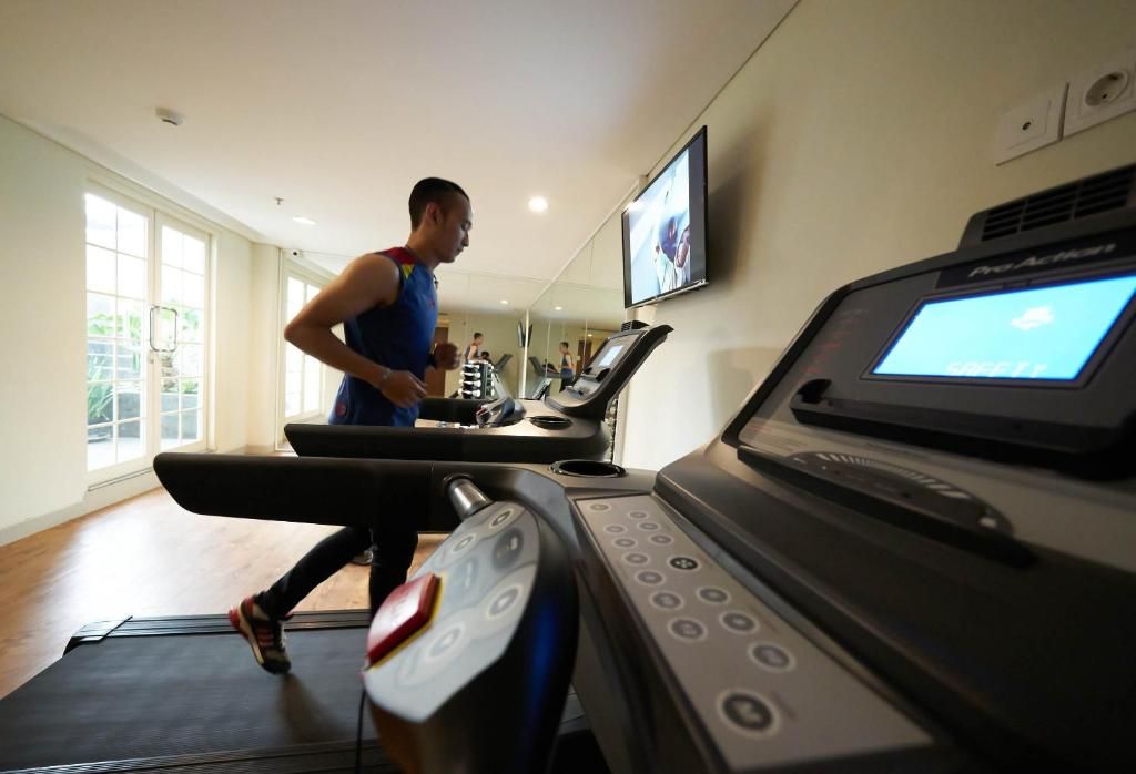 A person using a treadmill in a room with a large window, a television, and a ProACT Smart Fitness machine.