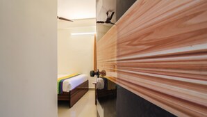 A hotel room with a bed, a nightstand, and a mirror. - Itsy Hotels Riyas Grand (Tirupati)