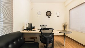 A modern office with a desk, two chairs, a black leather couch, and three clocks on the wall. - Itsy Hotels Riyas Grand (Tirupati)