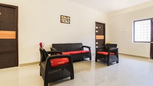 A room with a sofa and two chairs, a door, a window, and a wall-mounted picture. - Itsy Hotels Riyas Grand (Tirupati)