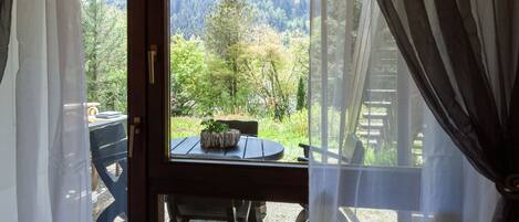 A room with a view of a forested area through a window.