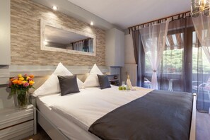 A modern bedroom with a large bed, a mirror, and a view of the outdoors.