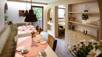 A dining area with a checkered tablecloth, set dining table, and a bench.