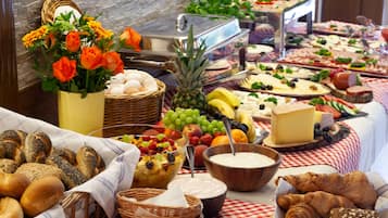 A buffet table with various food items and a decorative vase of orange flowers.