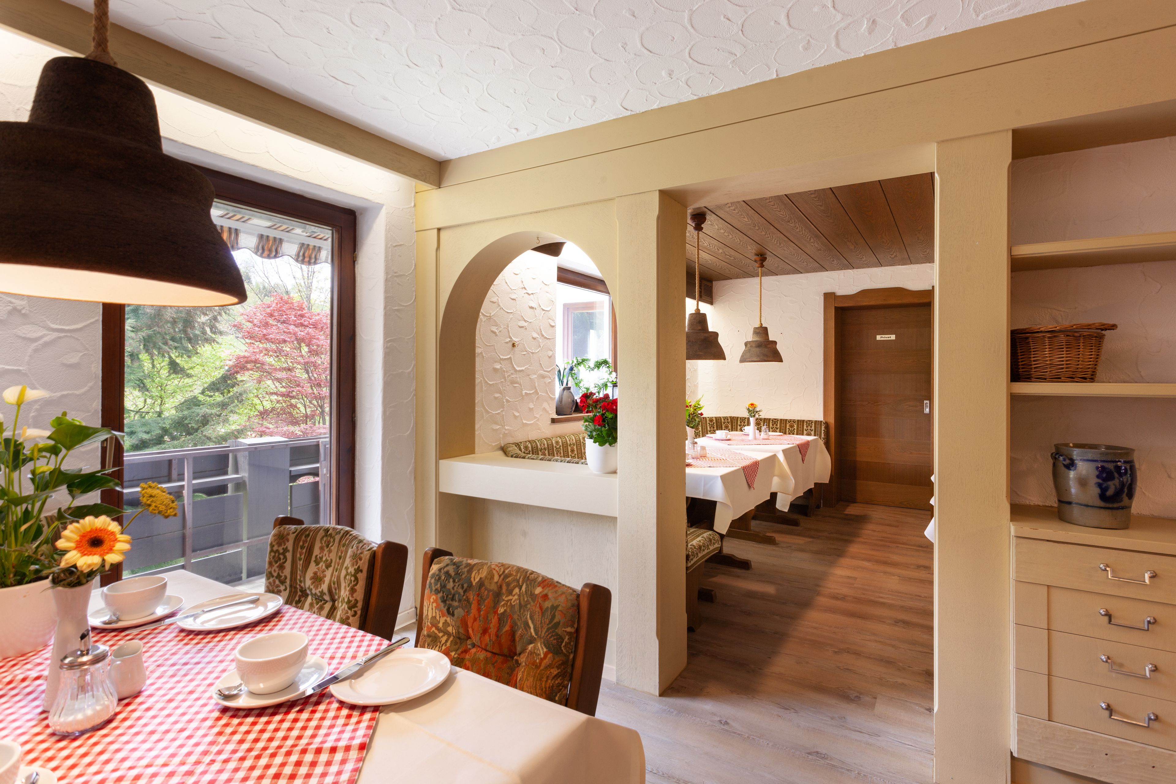 Un coin repas avec une nappe à carreaux, des chaises et un luminaire suspendu.