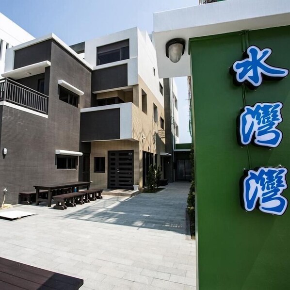 A modern building with a green signboard, outdoor seating, and a clear sky. - Hsu One One B&B (Magong)