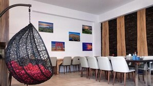 Un comedor moderno con una silla colgante, una mesa larga con sillas y obras de arte en las paredes.