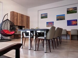 A modern dining area with a glass-top table, multiple chairs, and a hanging chair. - Hsu One One B&B (Magong)