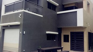 Un edificio moderno de dos pisos con balcón, garaje y mobiliario exterior.