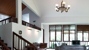 Un salon spacieux avec un escalier en bois, un lustre et de grandes fenêtres.