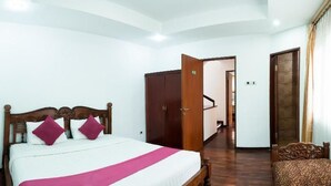 Une chambre d’hôtel comprenant un lit, une armoire et un petit coin salon.