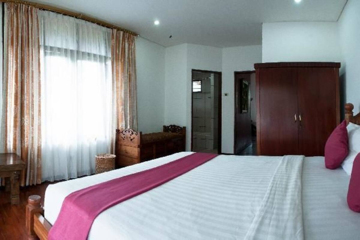 Une chambre d’hôtel comprenant un lit, un bureau avec une télévision, une armoire et une porte donnant sur une autre pièce.