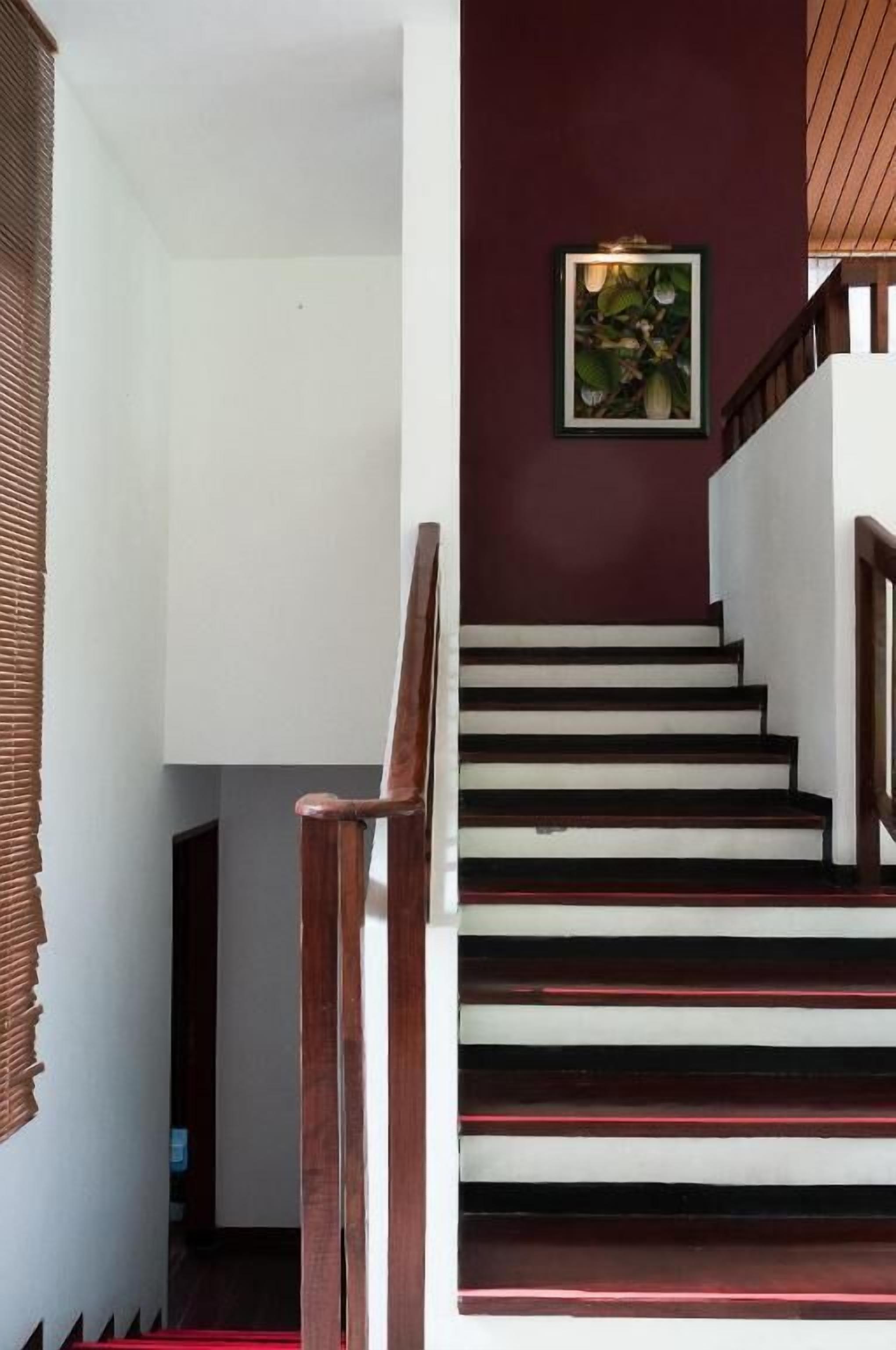 A staircase with wooden steps and a handrail, leading to a landing with a framed picture on the wall.