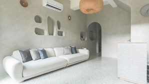Een moderne woonkamer met een witte modulaire bank, een bijzettafeltje en een uniek wandontwerp.