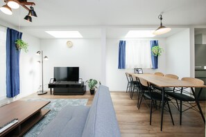 A modern living room with a sofa, TV, dining table, and chairs. - Higashi-Rokugo House WHITE by Tranova (Tokyo)