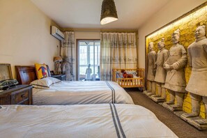 A hotel room with two beds, a wooden nightstand, a lamp, and a large wall mural of ancient warriors. - Xi'An Warriors Apartment (Xi'an)