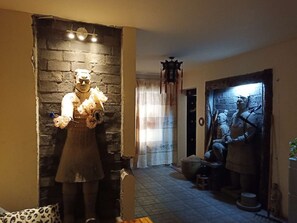 A room with a brick wall, a statue of a person holding flowers, a door with a mural, and a window with curtains. - Xi'An Warriors Apartment (Xi'an)