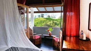 Una habitación con una cama, una pequeña mesa con un florero y vistas a un paisaje verde.