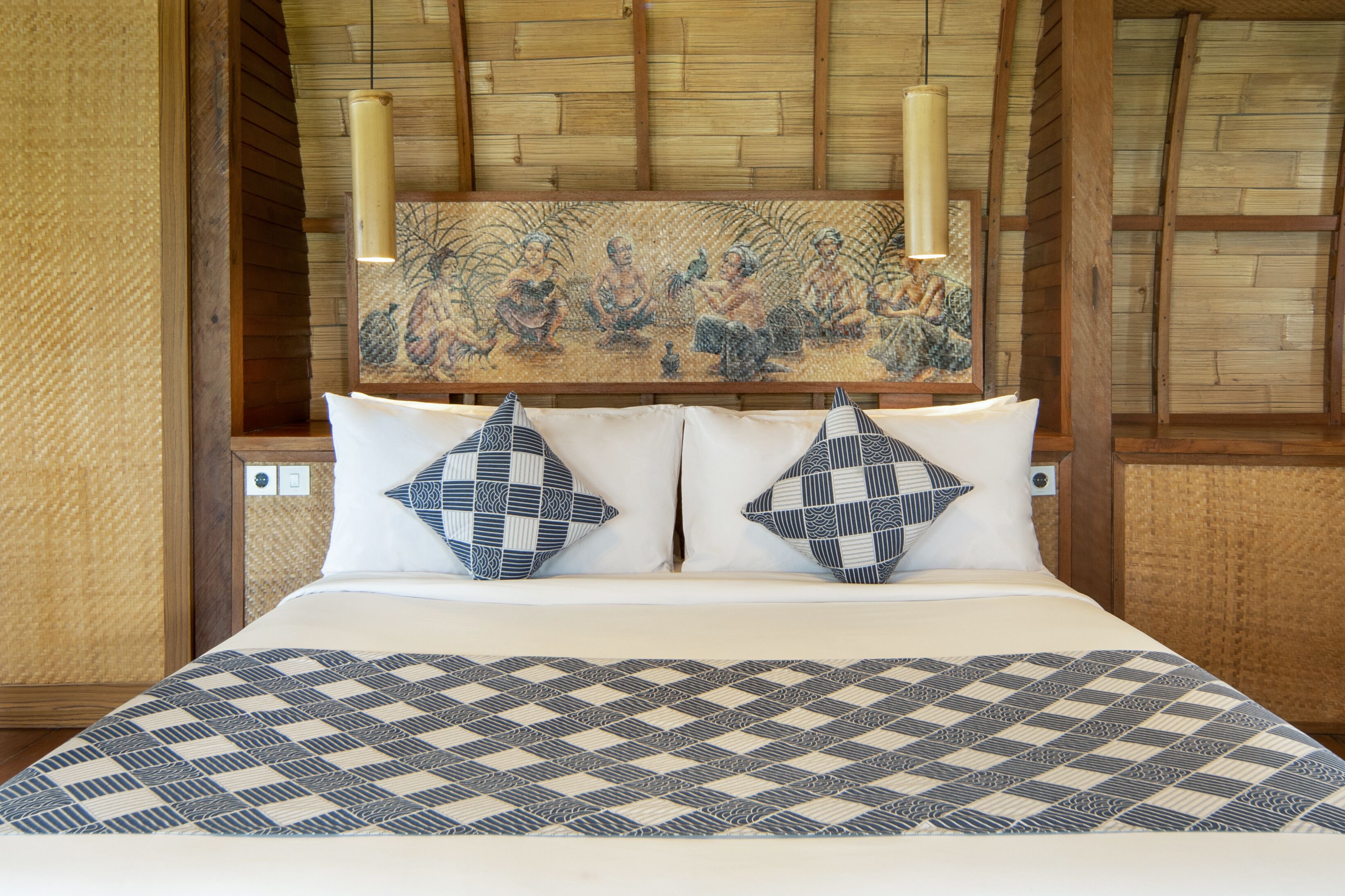 A bed with a checkered bedspread, two pillows with geometric patterns, and a wall-mounted artwork above.