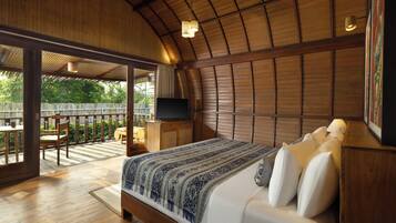 A bedroom with a wooden ceiling, a bed with white bedding, a TV on a wooden cabinet, and a balcony with a table and chairs.