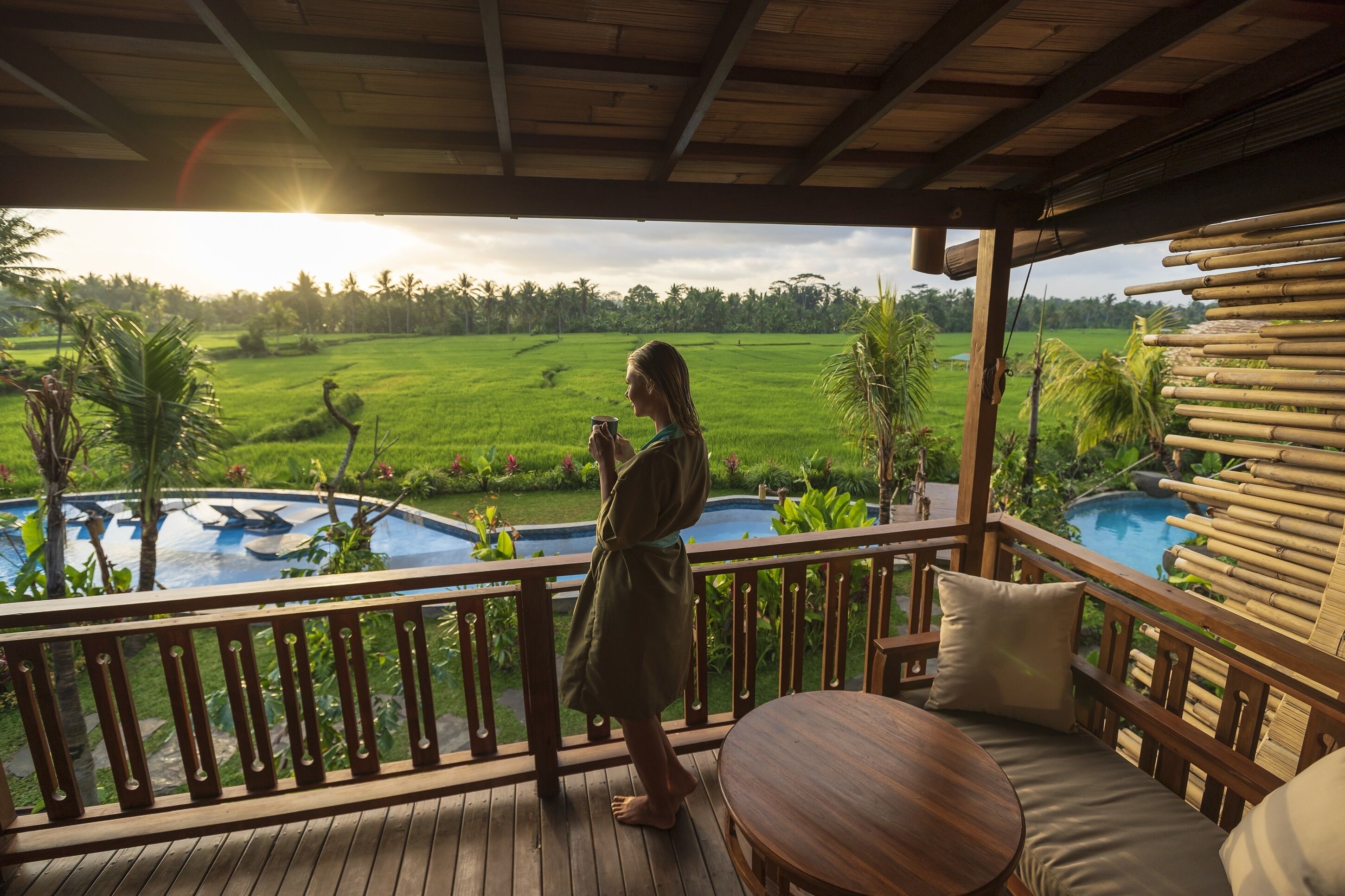 A wooden deck with a view of a swimming pool and lush greenery.