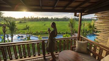 A wooden deck with a view of a swimming pool and lush greenery.