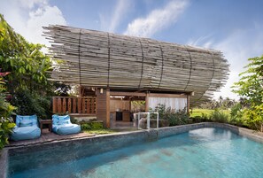 Ein moderner Poolbereich mit einer Bambuskonstruktion, einem Pool und zwei blauen Sitzsäcken.