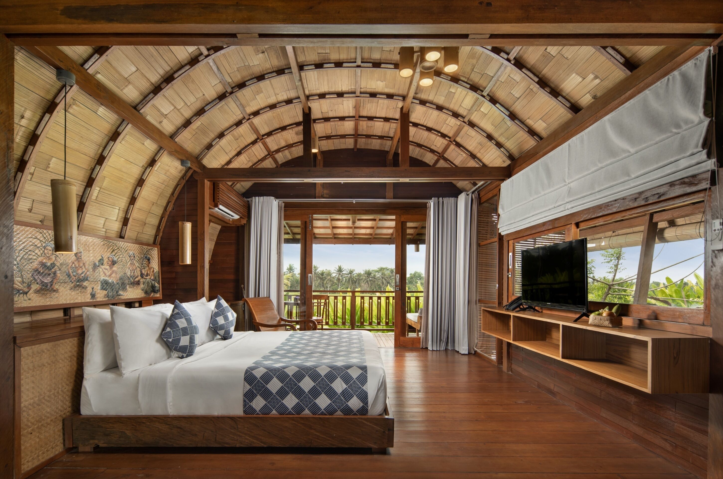 A bedroom with a large bed, wooden ceiling, and a TV on a wooden stand.