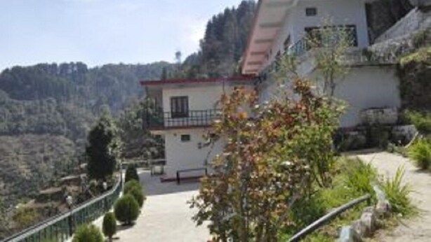 A two-story building with a balcony, surrounded by greenery and a mountainous landscape. - Hotel Garden Cottage & Resort Dhanaulti (Dhanaulti)