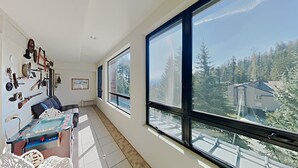 A spacious room with large windows, a sofa, a table with a board game, and various items on the wall. - Great 2 Bedroom Condo with Amazing Views! Access to Hot Tubs and Heated Pool! (Unit 307 at 1849) by RedAwning (Mammoth Lakes)