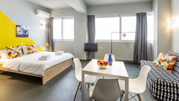 Een moderne hotelkamer met een bed, een bank, een eettafel en een televisie.