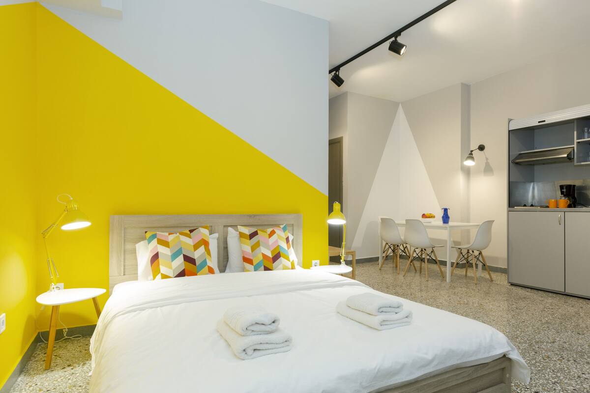 A hotel room with a bed, a desk, and a kitchenette.