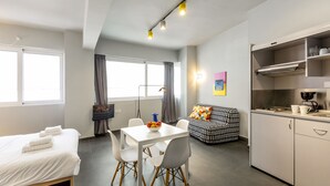 Een moderne hotelkamer met een bed, een eettafel met stoelen, een kitchenette en een bank.