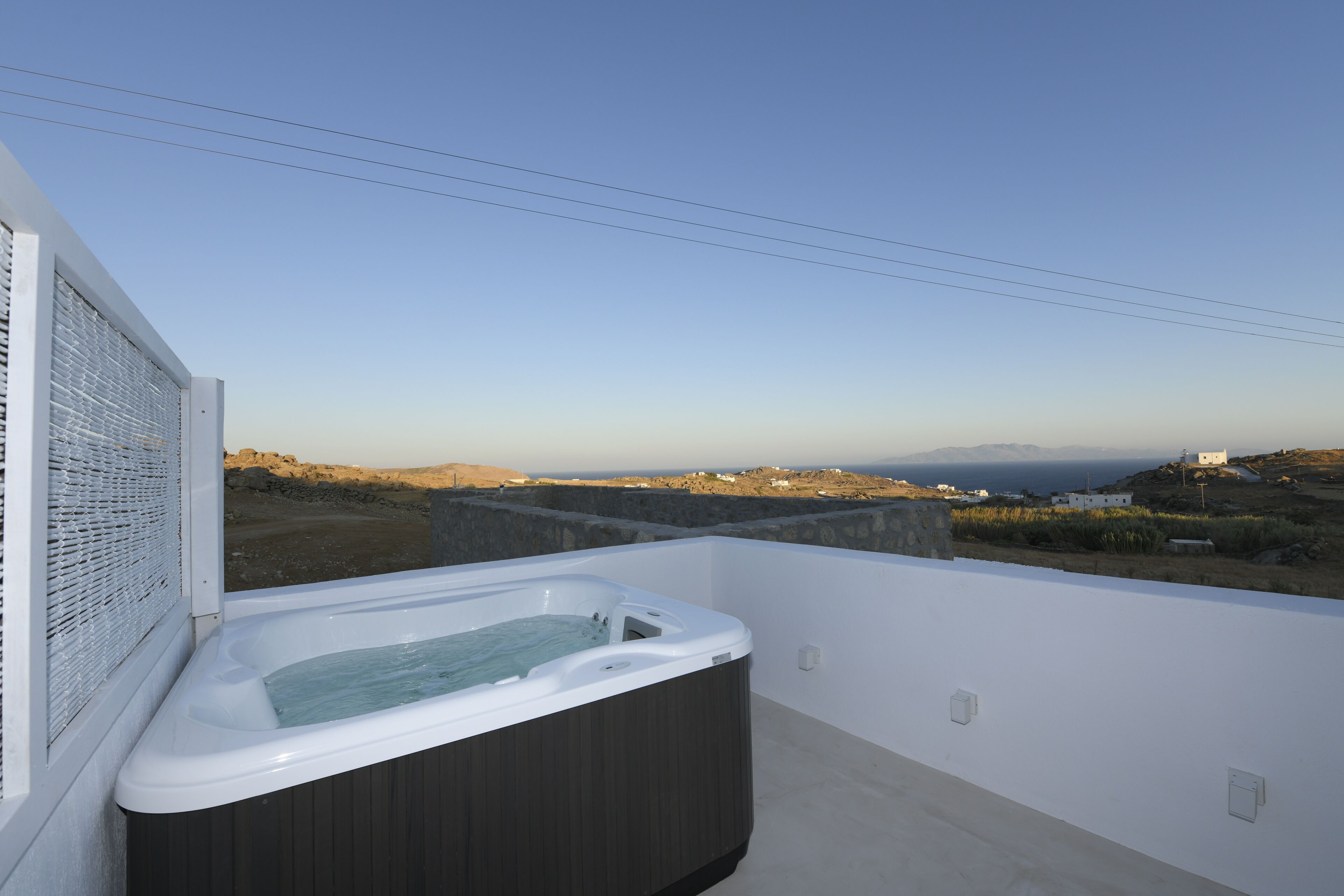 A hot tub on a balcony with a view of a coastal landscape.